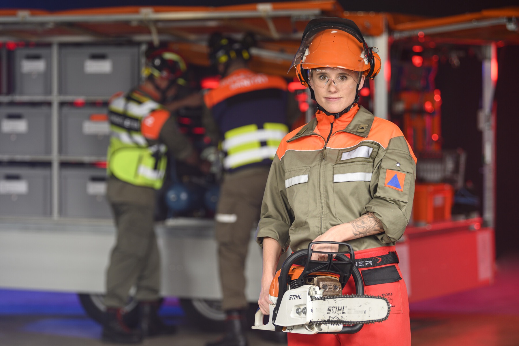 Membre de la protection civile avec une tronçonneuse devant un véhicule d’intervention